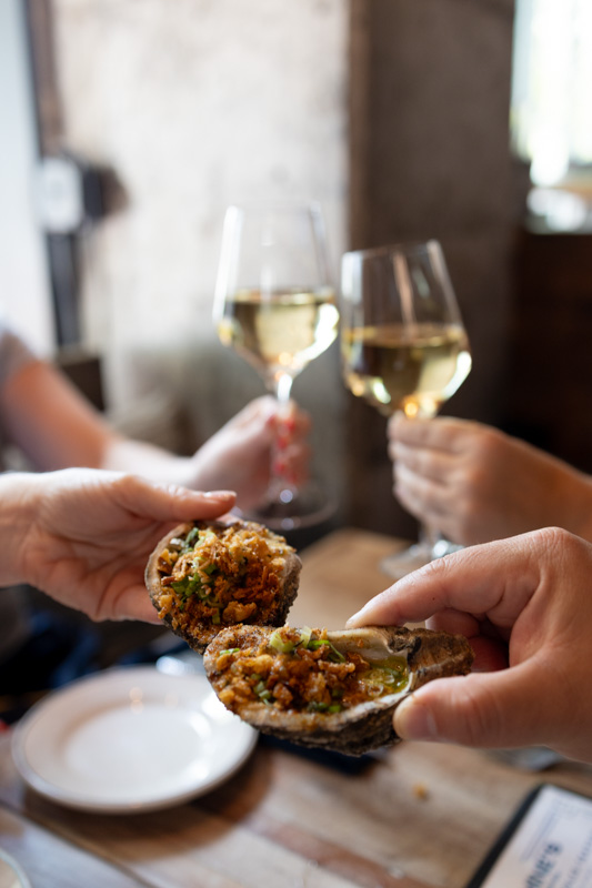 People cheersing with wine and oysters